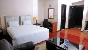 Habitación de hotel con cama, escritorio, silla, mesa de centro y espejo.