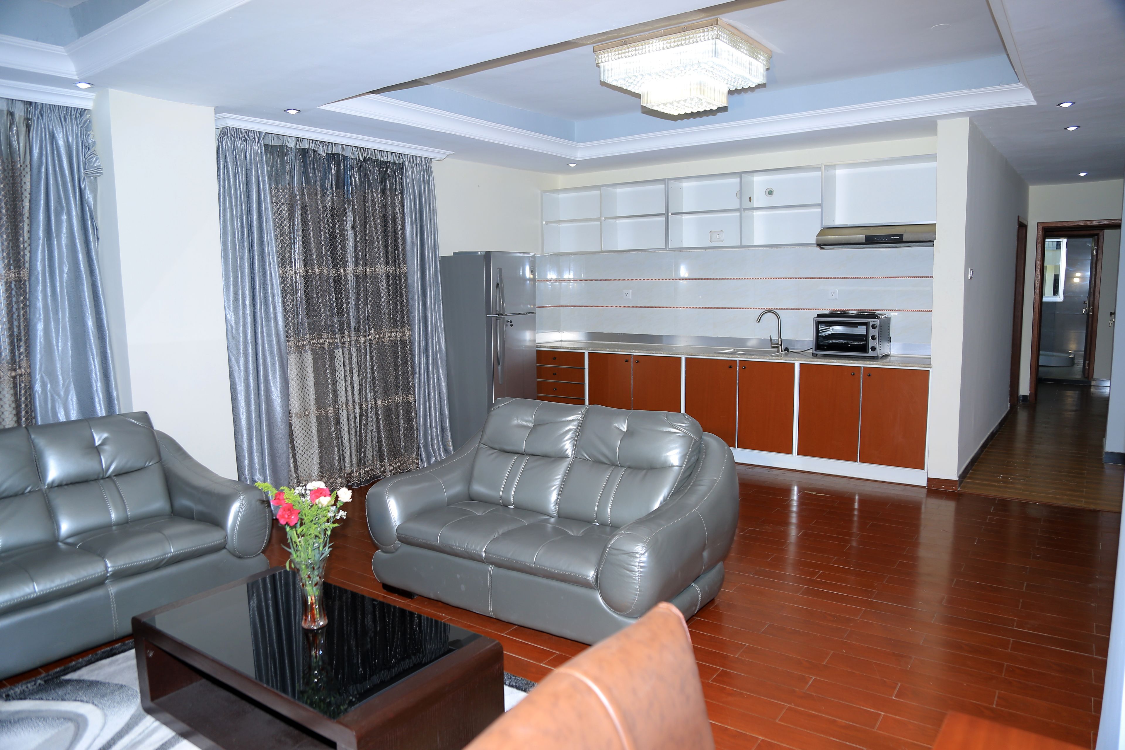 A modern living room with a sofa, a coffee table, and a kitchen area in the background.