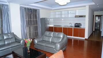 A modern living room with a sofa, a coffee table, and a kitchen area in the background.
