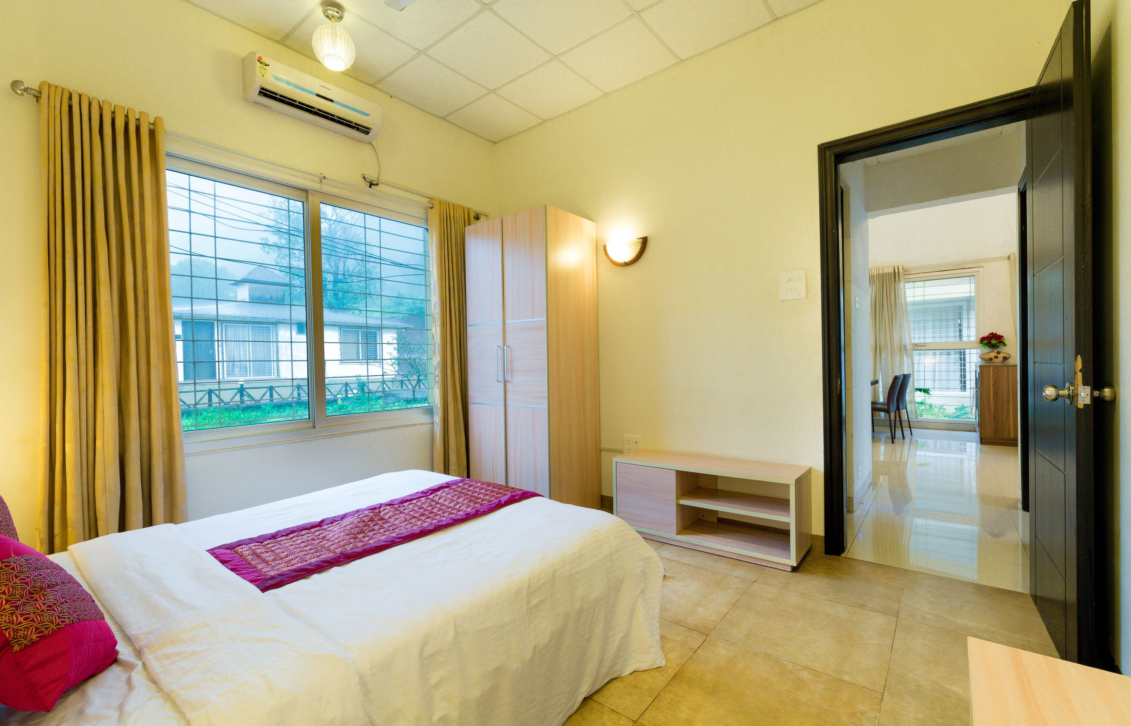 A hotel room with a bed, a wardrobe, a desk, and a door leading to a balcony.