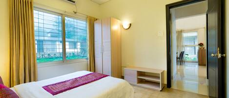 A hotel room with a bed, a wardrobe, a desk, and a door leading to a balcony.