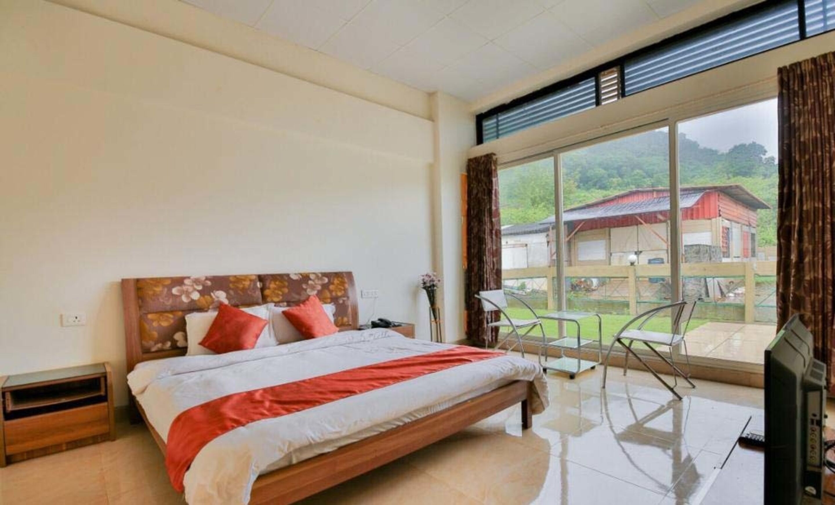 A bedroom with a bed, a desk, and a view of a rural landscape.