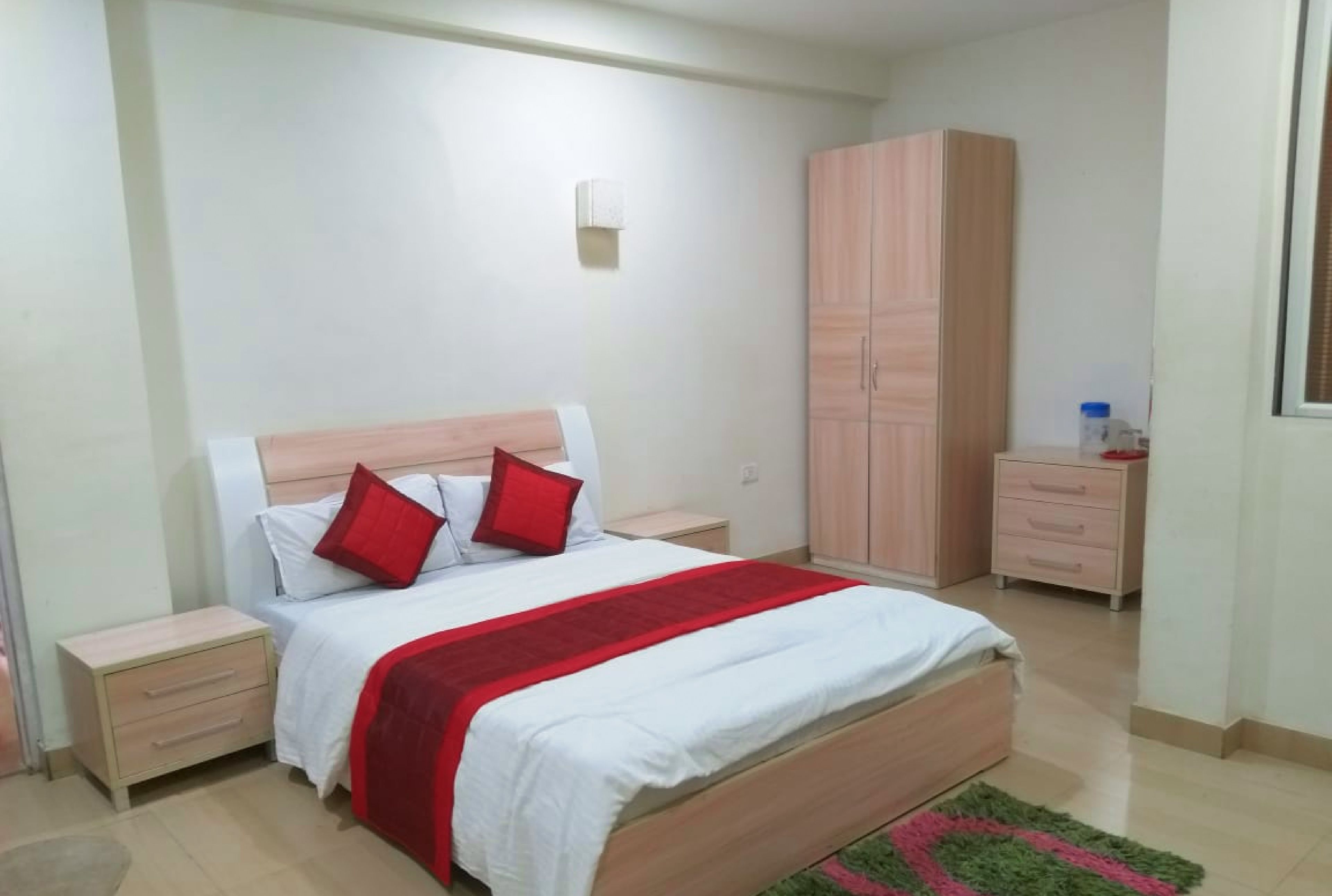 A bedroom with a bed, nightstands, a wardrobe, and a small table.