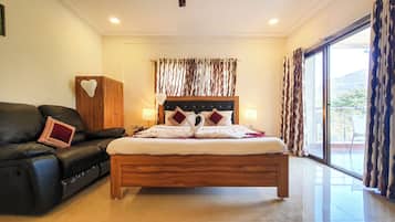Un dormitorio con cama de madera, sofá de cuero negro y vistas al exterior a través de un gran ventanal.
