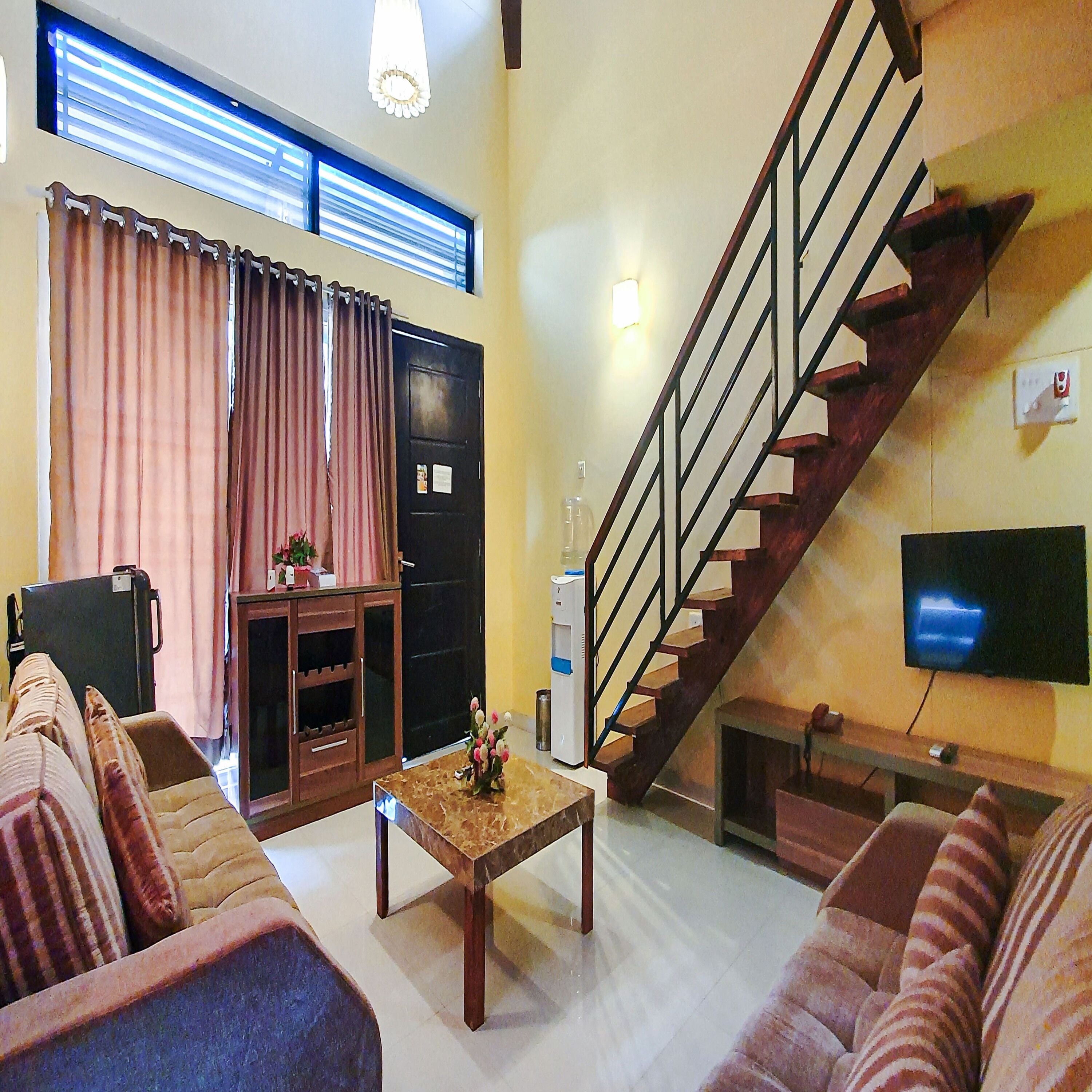 A living room with a sofa, a coffee table, a TV, and a staircase.