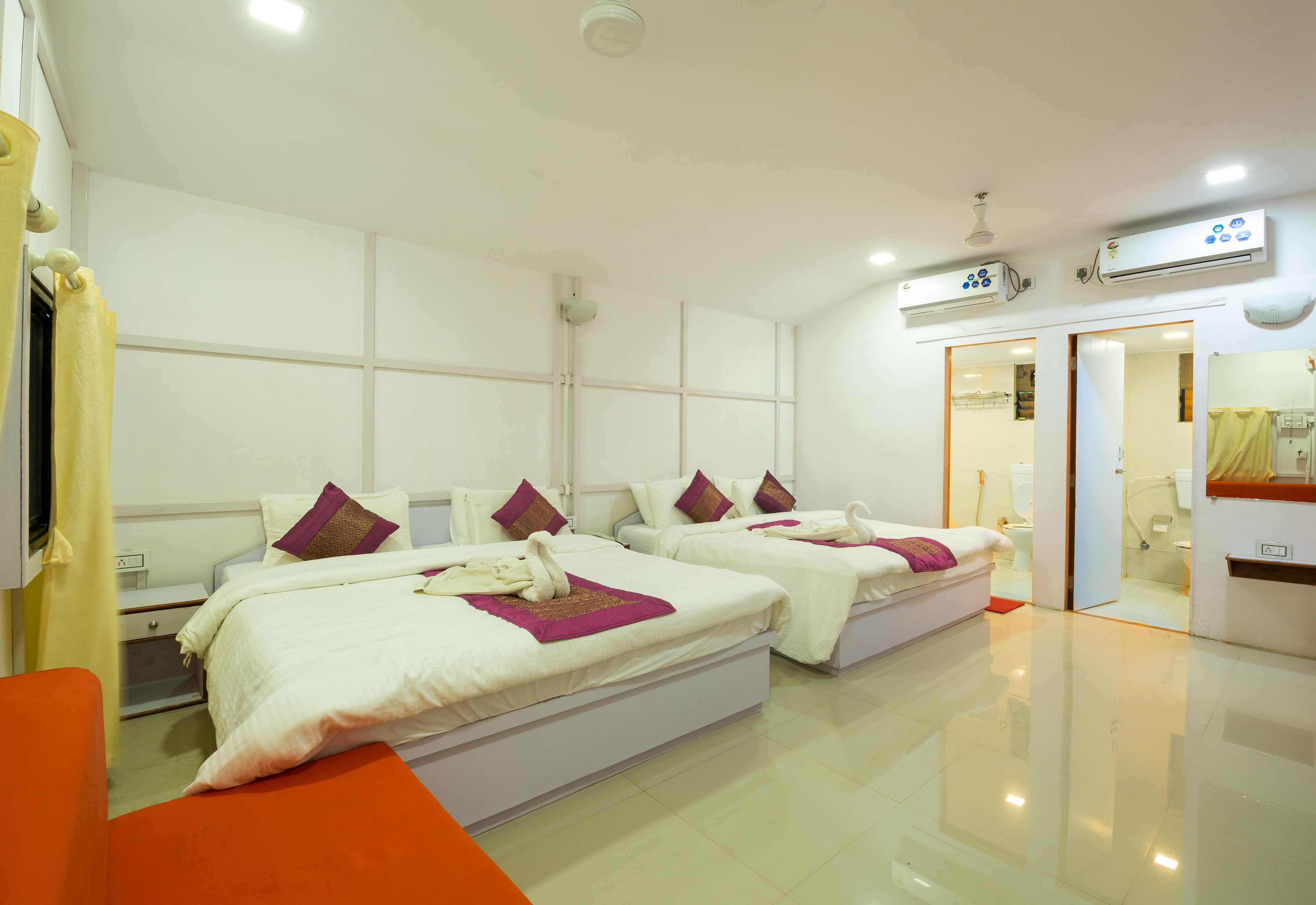 A hotel room with two beds, a bathroom, and a mirror.