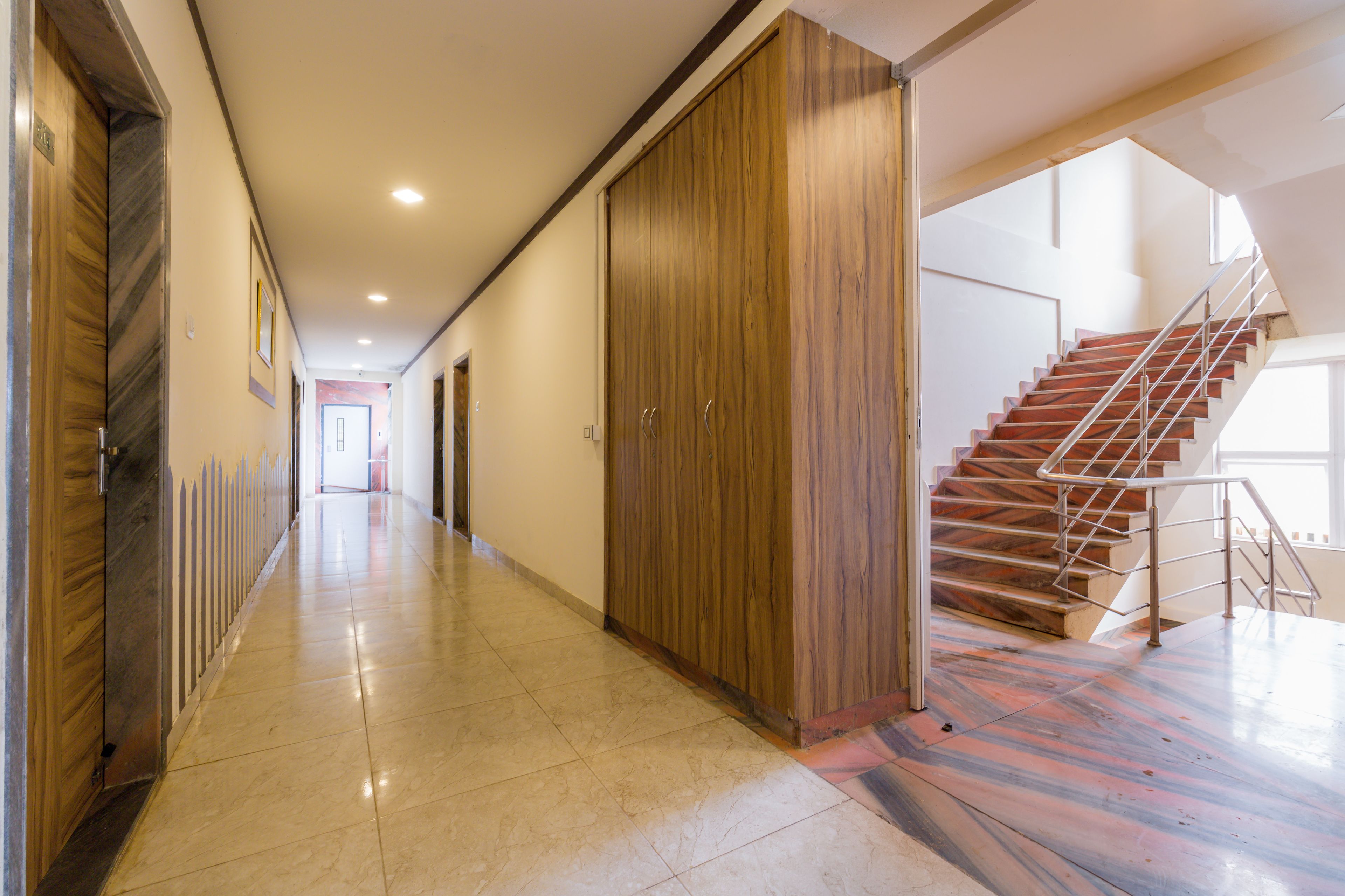 Un pasillo con un armario de madera, una escalera y suelo de baldosas.