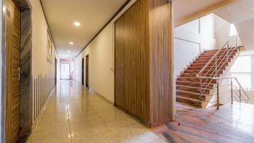Un pasillo con un armario de madera, una escalera y suelo de baldosas.