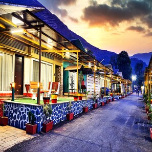 A row of brightly lit, modern buildings with large windows and a stone facade. - Rainforest Resort By Aralia, Igatpuri (Igatpuri)
