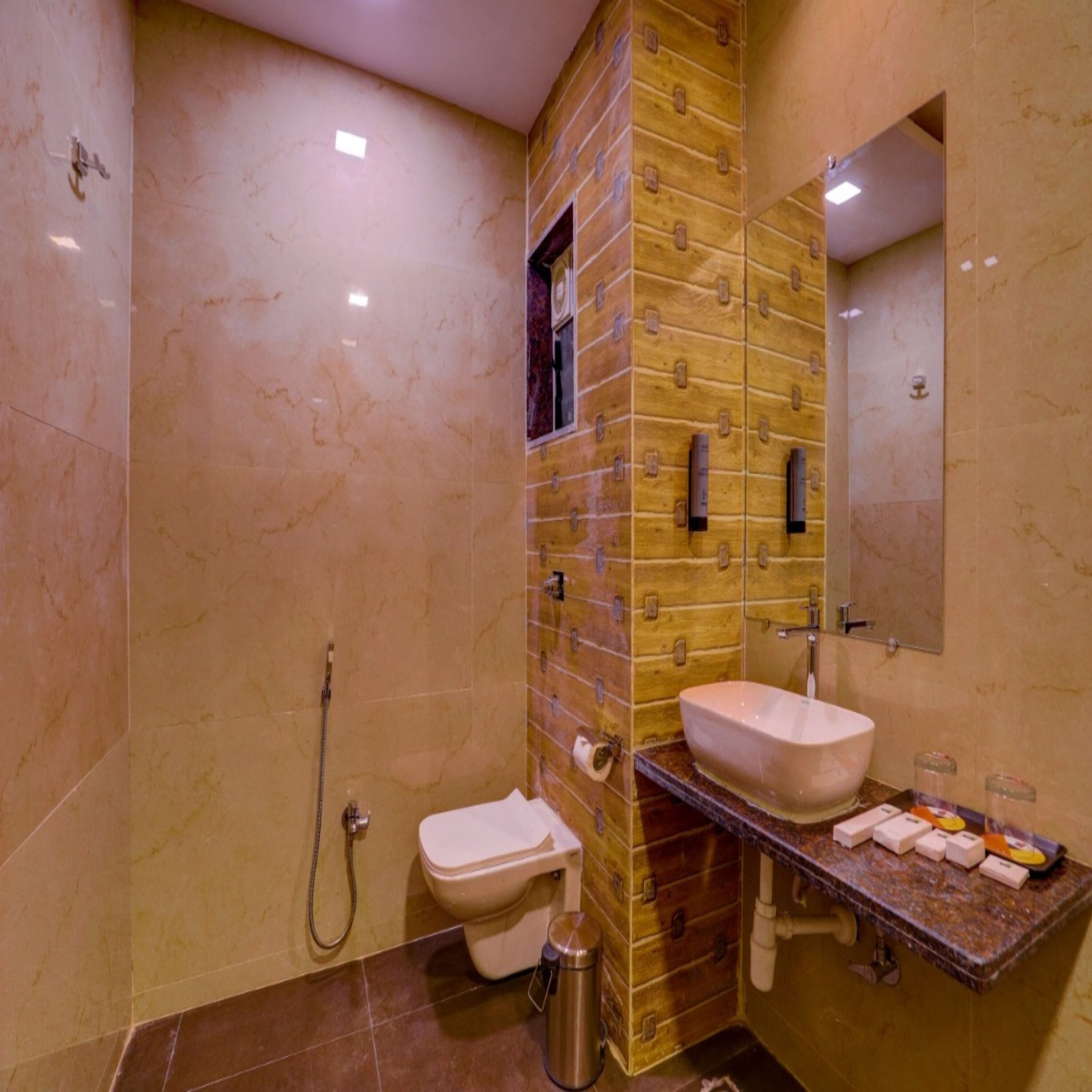 A bathroom with a marble floor, a wooden vanity, a sink, a toilet, and a shower.