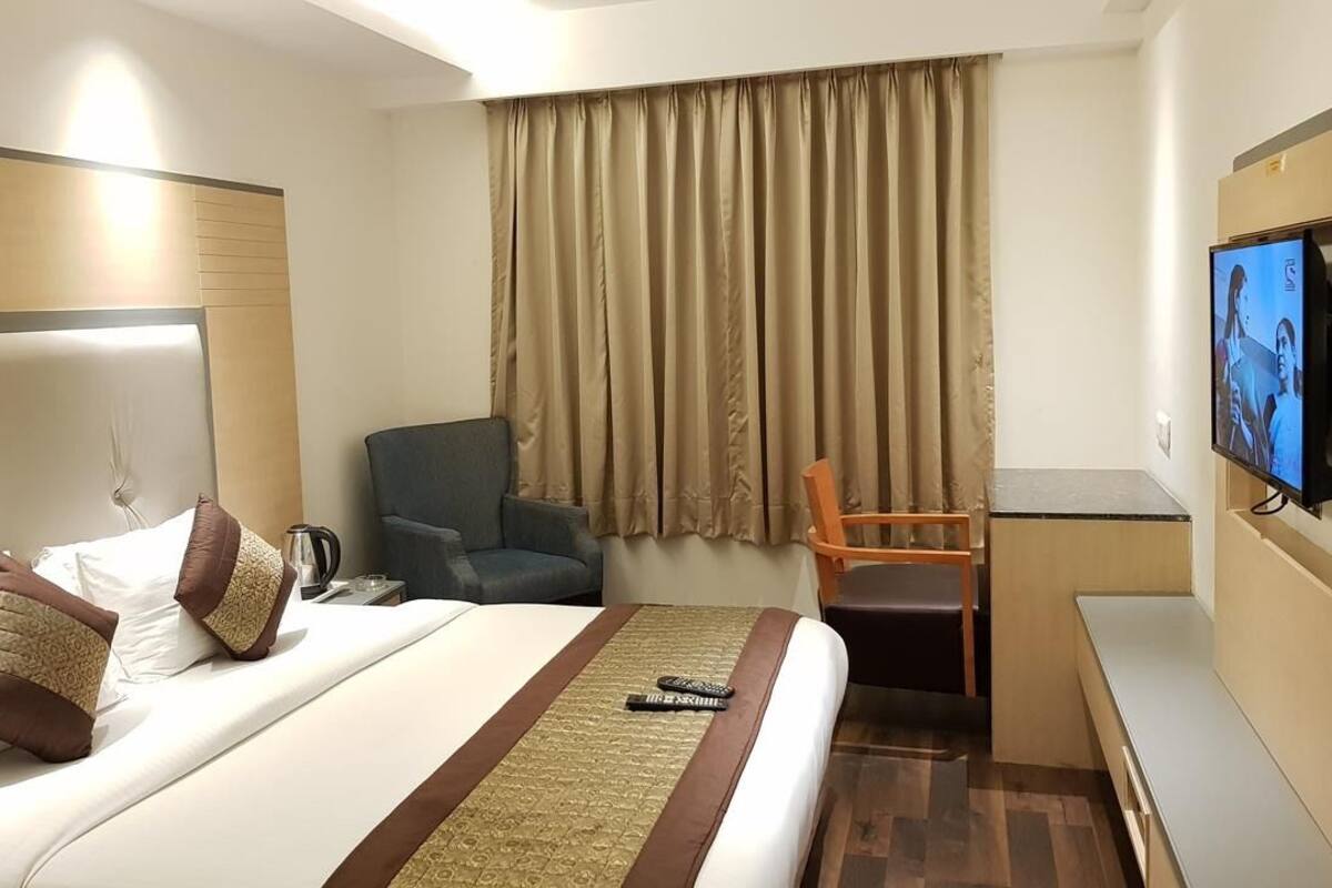 Una habitación de hotel con cama, escritorio, silla y televisor.