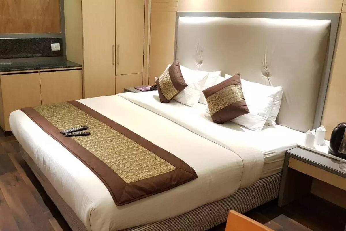 Una habitación de hotel con una cama grande, una mesita de noche con lámpara y un armario.