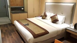 Une chambre d’hôtel avec un grand lit, une table de chevet avec une lampe et une armoire.