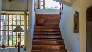 Un escalier en bois avec un mur en briques, une fenêtre avec une lampe et un vase sur la plateforme.
