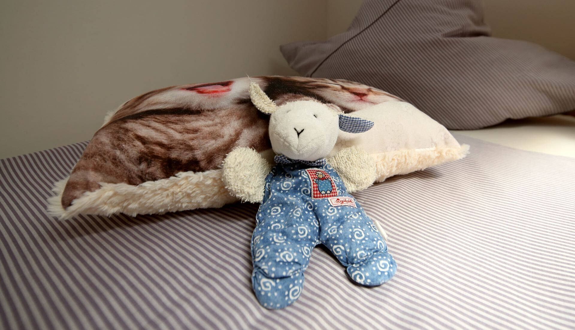 A plush toy with a tag on a striped bedspread.