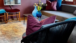 Ein modernes Wohnzimmer mit einer Couch, einem schwarzen Sessel, einem Couchtisch, einem Fernseher und einer Vase mit Blumen.