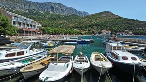 A marina with boats docked, a restaurant named "Caffè Restaurant" on the left, and a mountainous backdrop. - Gorgeous home in Drvenik with WiFi (Drvenik)