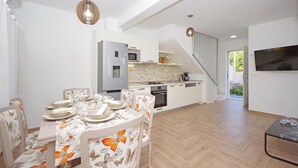 A modern kitchen with a built-in fridge, microwave, and stove. There is a dining area with a table set for four, and a staircase leading to an upper level. - Gorgeous home in Drvenik with WiFi (Drvenik)