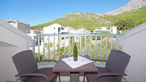 A balcony with a table and two chairs, overlooking a hillside with buildings. - Gorgeous home in Drvenik with WiFi (Drvenik)