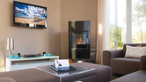 Un salon moderne avec un téléviseur à écran plat, une cheminée, un canapé et une table basse.