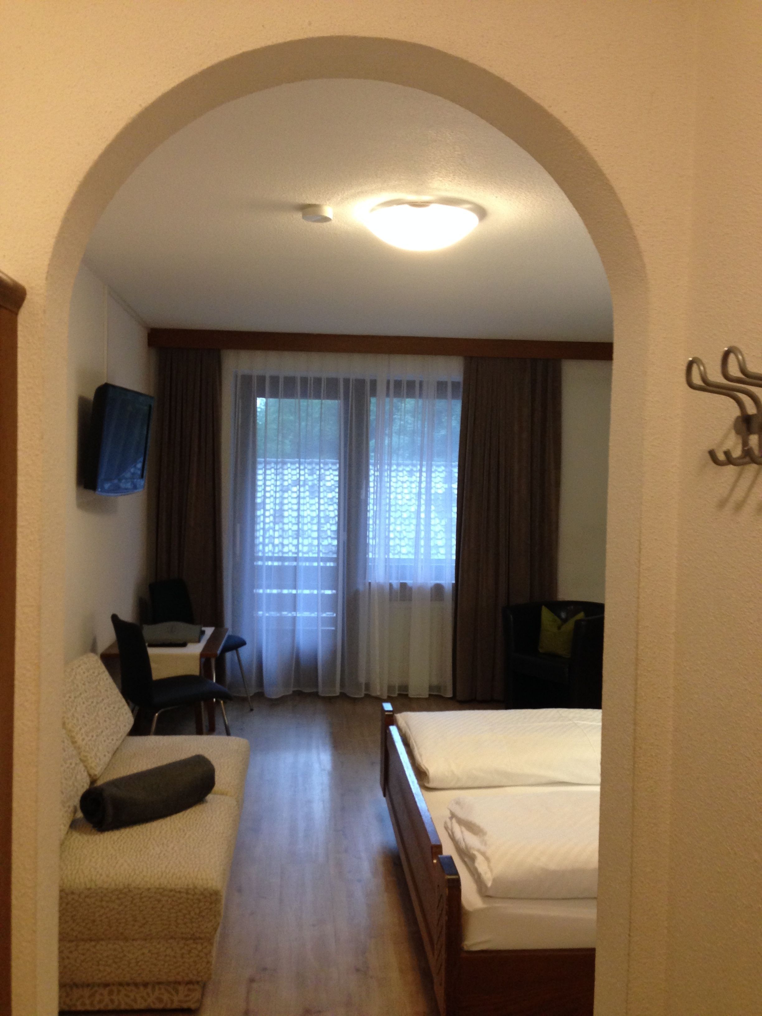 A hotel room with a bed, a sofa, a desk, and a television.