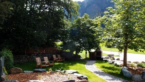 A patio area with outdoor seating and a stone wall. - Alpinhotel Zerres (Gaschurn)