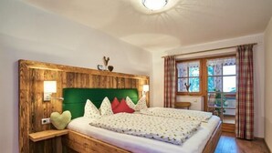 Un lit en bois avec une tête de lit verte, deux lampes de chevet et une fenêtre avec des rideaux.