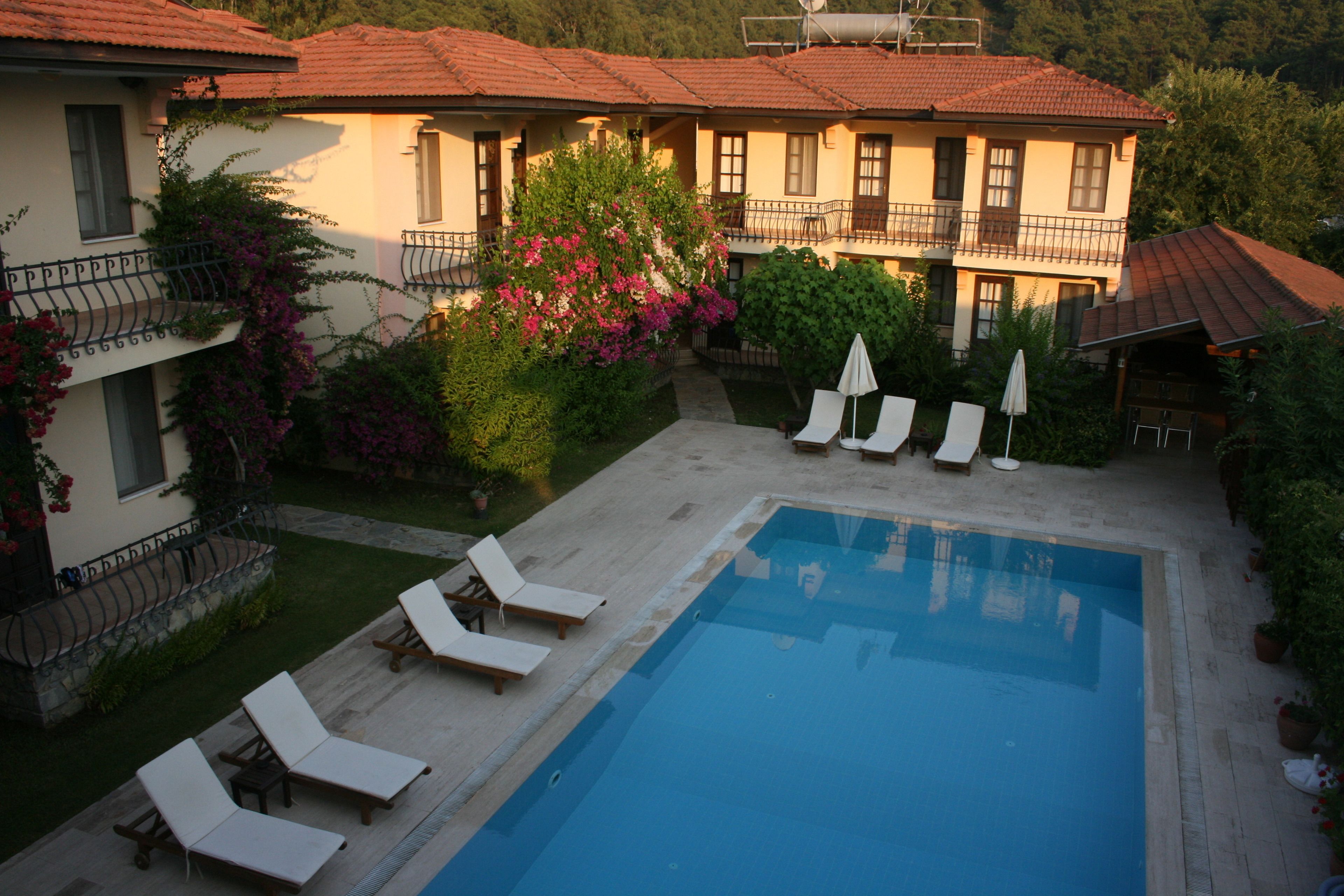 A pool area with lounge chairs, a clear pool, and a building with balconies.