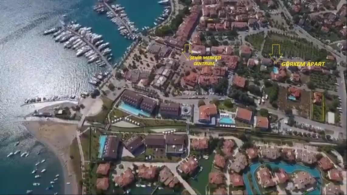 An aerial view of a coastal area with a marina, a central building labeled "Şehir Merkezı CENTRUM," and a labeled area "GÖRKEM APART."