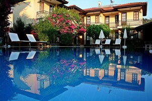 Una piscina con agua cristalina que refleja los edificios circundantes y la exuberante vegetación.