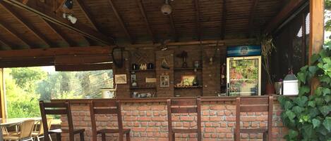 Una zona de bar con pared de ladrillo, sillas de madera y una barra.