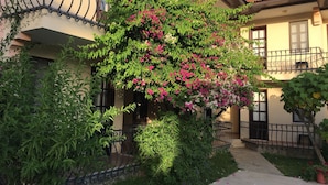 A residential building with a balcony, a garden with flowering plants, and a satellite dish on the roof. - Gorkem Apart Hotel (Fethiye)