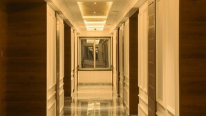 Un pasillo largo y estrecho con piso de mármol pulido y paneles de madera en las paredes.