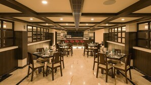 Un restaurante espacioso con techos altos, paneles de madera oscura y una zona de bar central.