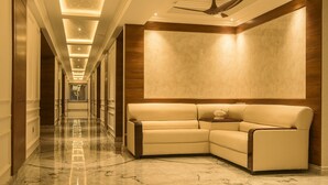 Un vestíbulo de hotel con suelo de mármol, un sofá de cuero y un ventilador de techo.
