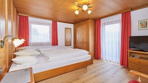 Een kamer met houten lambrisering, een bed, een televisie en een houten dressoir.