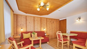 Een knus vertrek met houten wanden, een rode bank, een houten tafel en bijpassende stoelen.