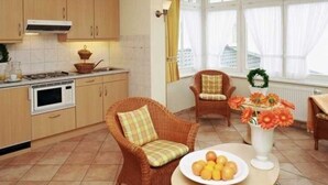 Une cuisine avec des chaises en osier, une table à manger et une fenêtre avec des rideaux.