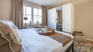 Une chambre d’hôtel avec un lit, un plateau de petit-déjeuner, une fenêtre, une armoire et une vue sur la ville.