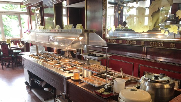A buffet setup with multiple food stations and a beverage dispenser. - Simona Hotel Frankfurt Airport (Hofheim am Taunus)