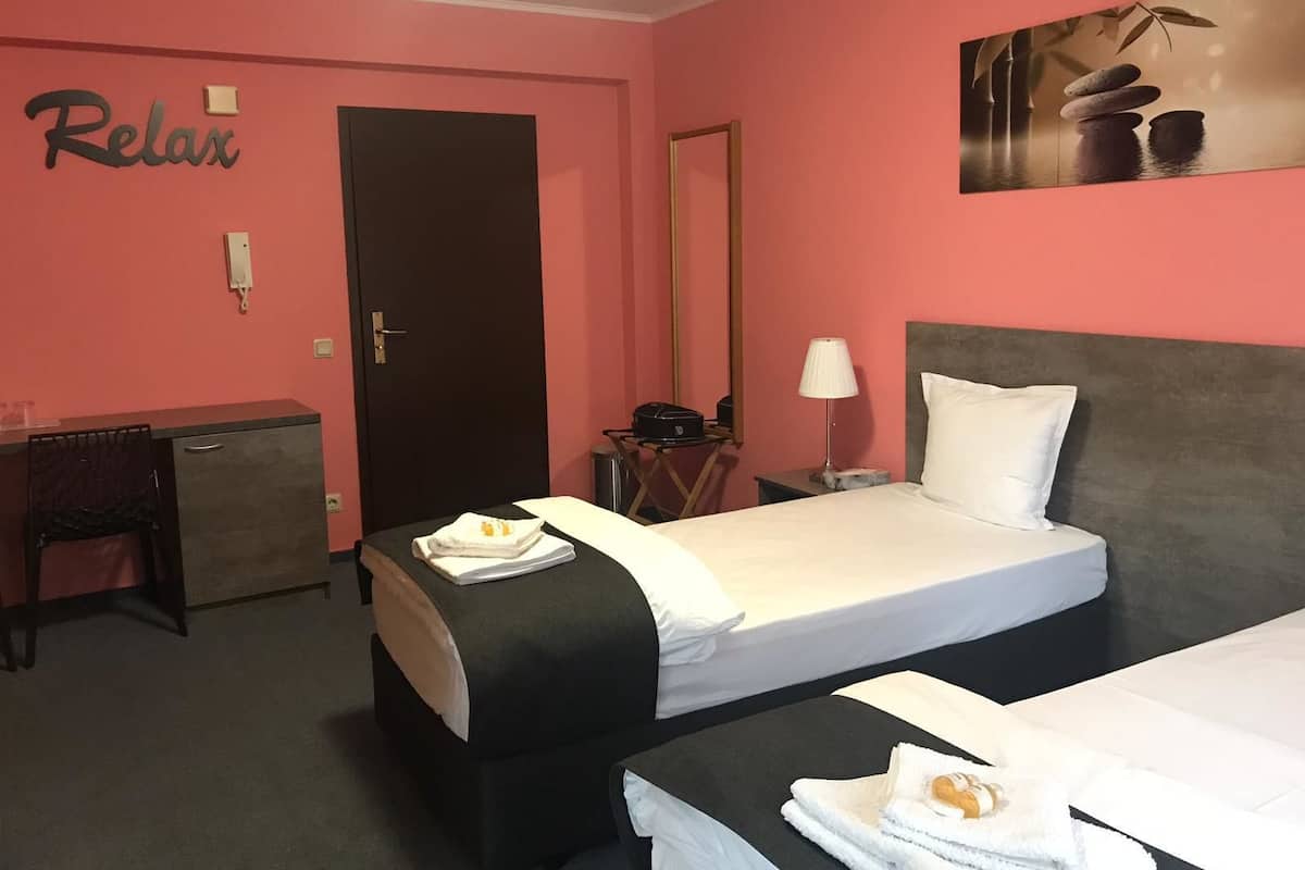 Une chambre d’hôtel avec deux lits, un bureau, une chaise et un tableau au mur.