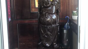 A statue of a seated figure with raised hands, a decorative mirror, and a trash can with an umbrella. - Simona Hotel Frankfurt Airport (Hofheim am Taunus)