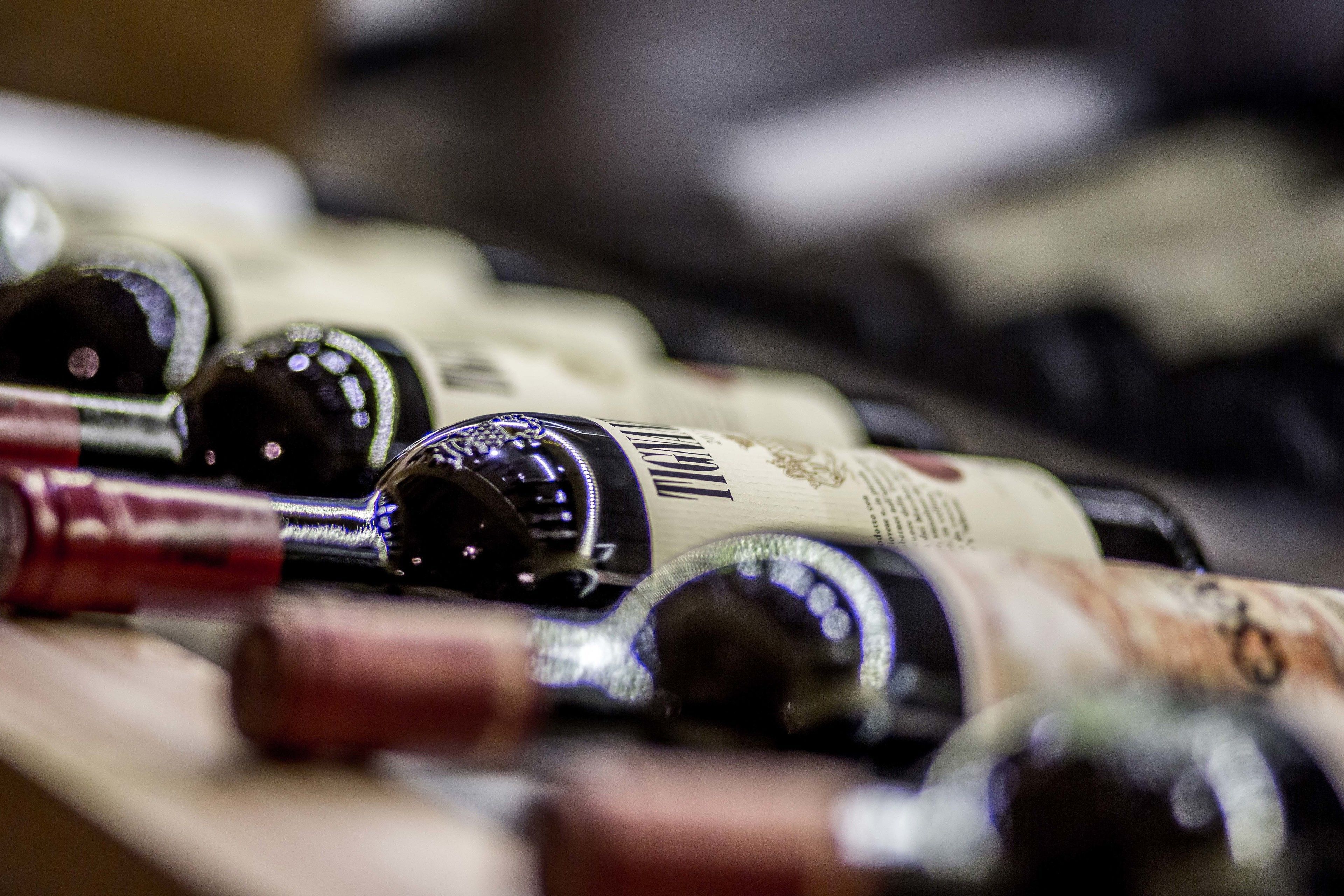 A close-up of wine bottles with labels, arranged on a surface.