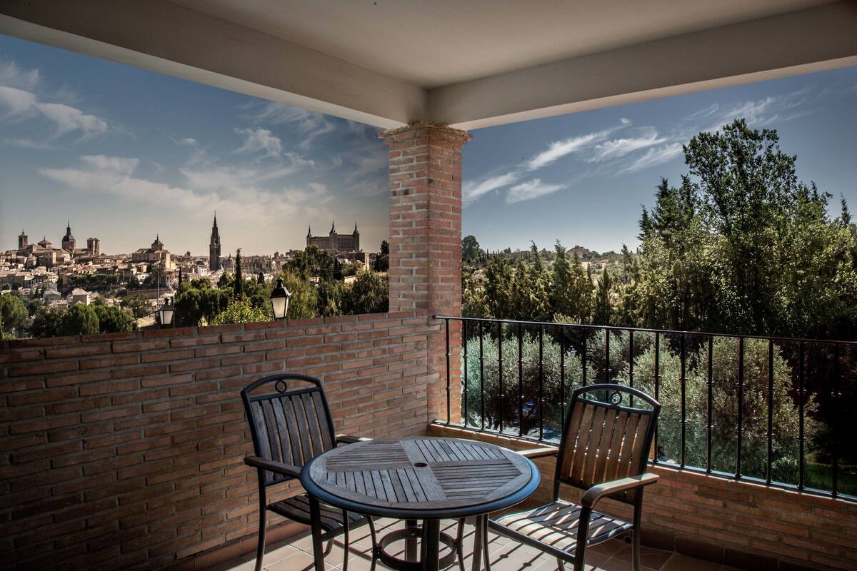 A balcony with a brick wall, two chairs, and a table.