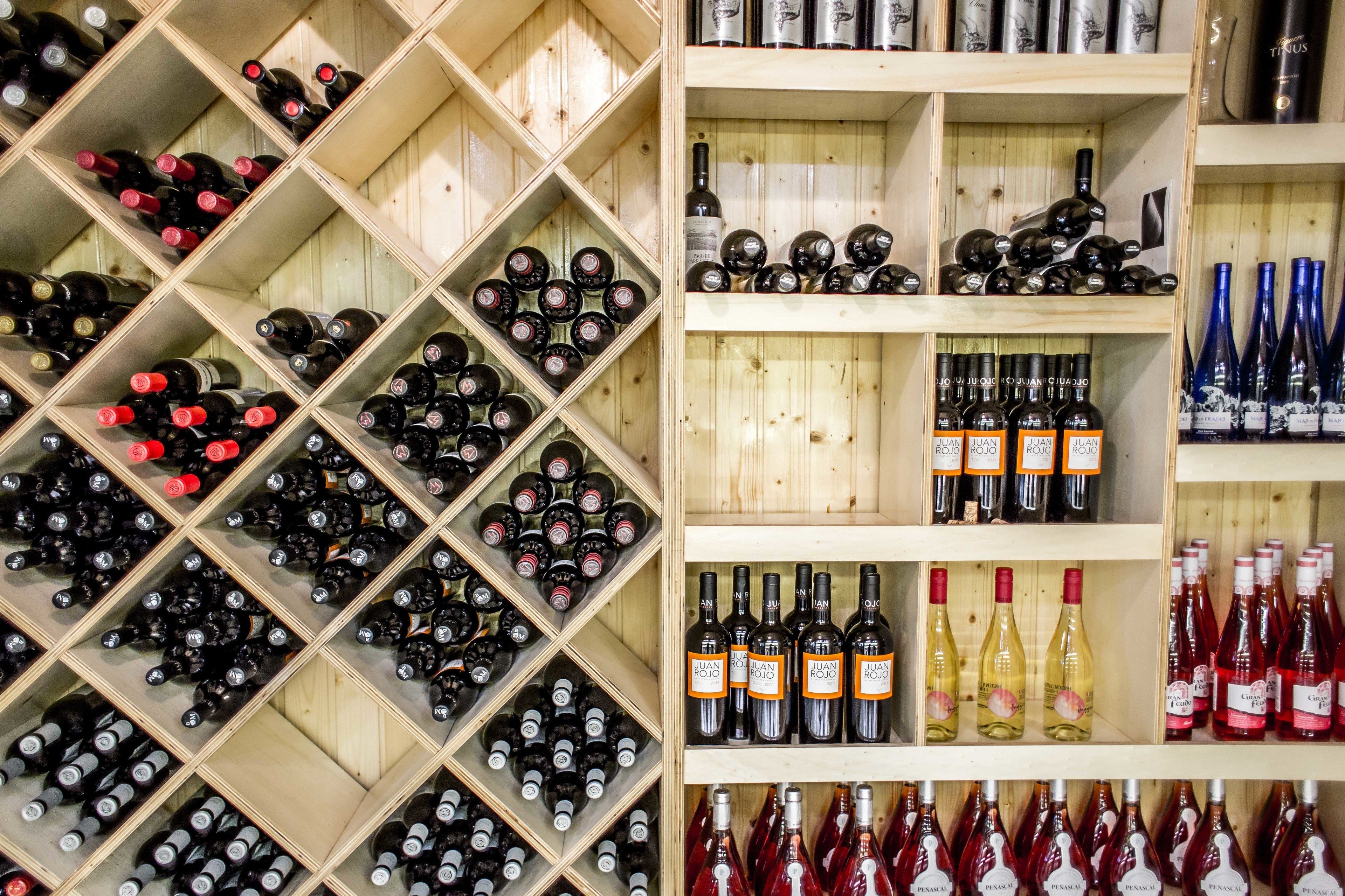 Una bodega con estantes y cavas de madera llenas de diferentes botellas de vino.