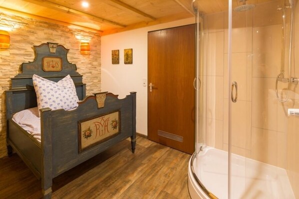 A bedroom with a wooden bed, a shower, and a door. - Apartment Zellerberg 40 sqm, balcony, kitchen, WLAN, 1 bedroom and 1 living room (Ruhpolding)
