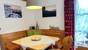 Un coin accueillant avec une table en bois, des bancs et une fenêtre agrémentée de rideaux.
