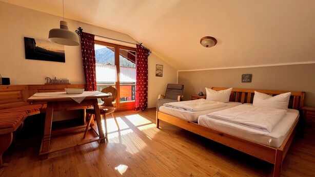 Une pièce avec un lit en bois, un bureau avec une chaise, une fenêtre avec des rideaux et un luminaire au plafond.