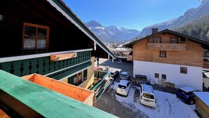 Un village de montagne avec des bâtiments en bois, un balcon et des voitures garées.