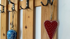 Un mur en bois orné de deux crochets métalliques, dont l’un supporte un ornement bleu et l’autre un ornement rouge en forme de cœur.